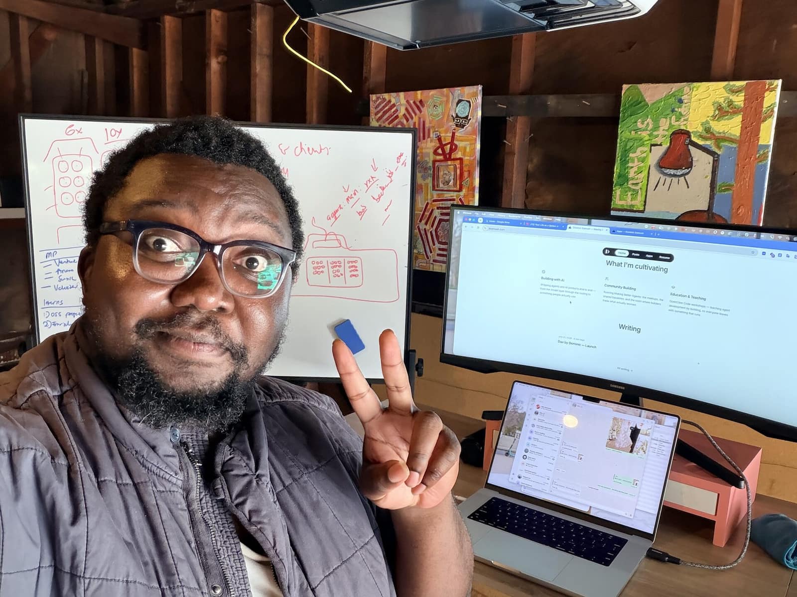 Dominic at his desk, a whiteboard covered in red diagrams behind him and his site open on the monitor.