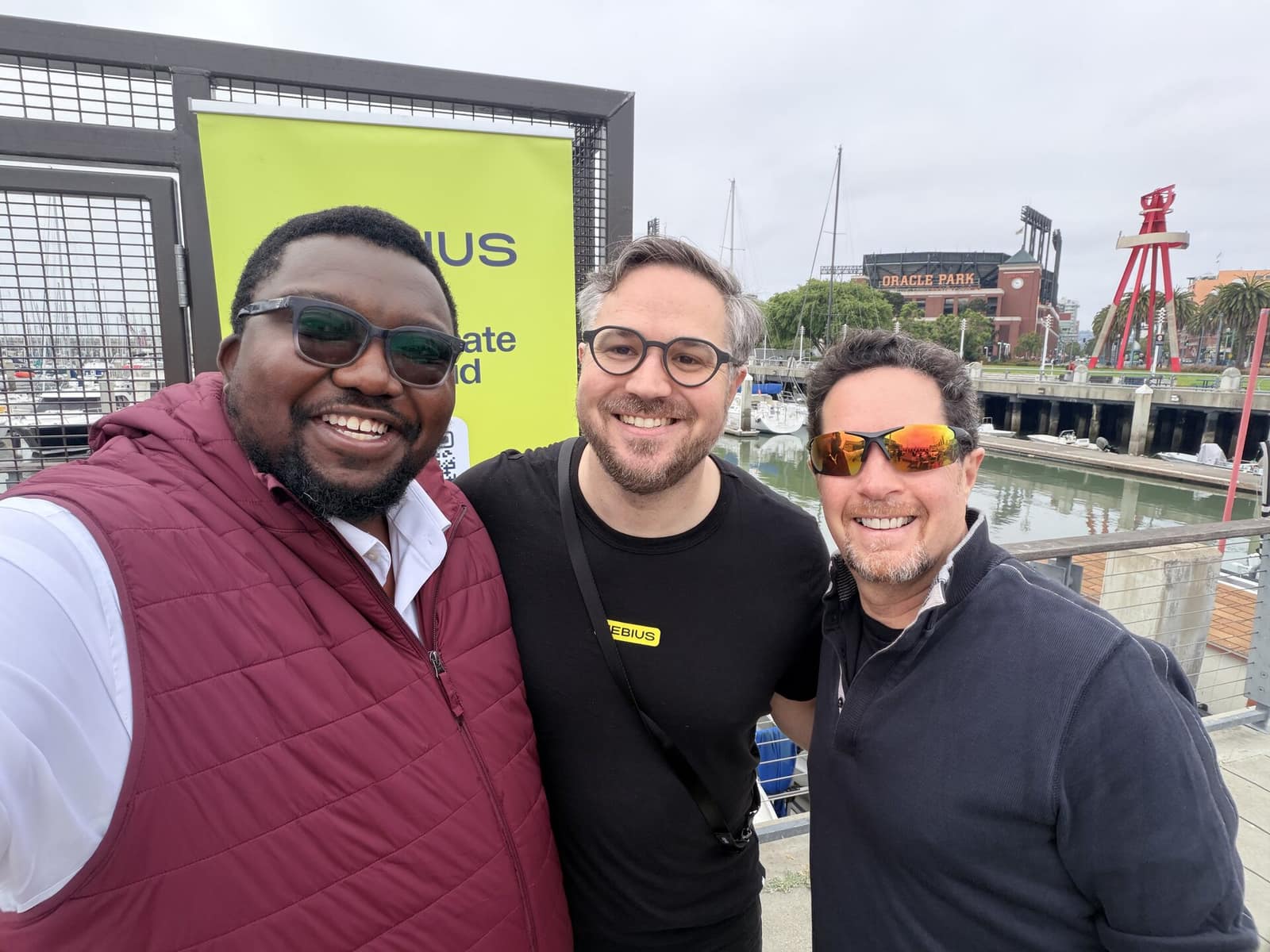 Dominic with two builders at an event on the San Francisco waterfront, Oracle Park in the background.