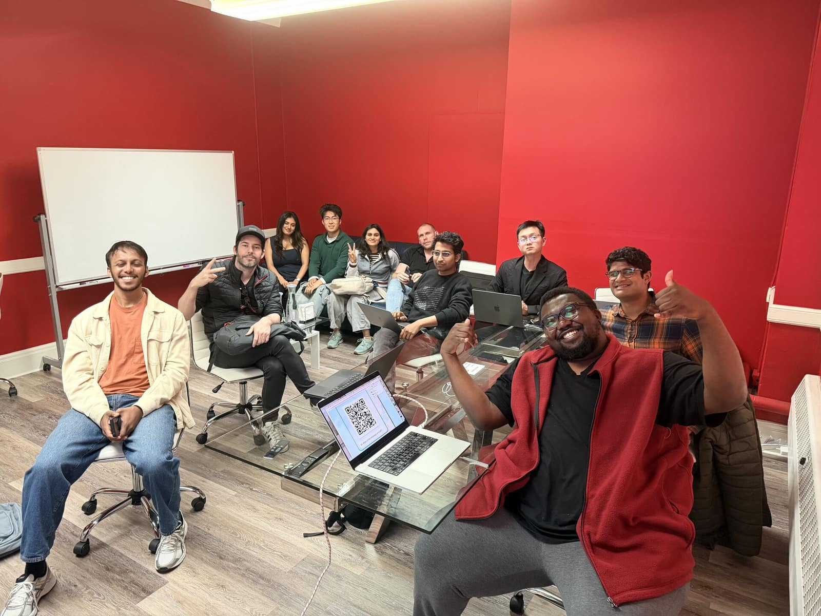 A workshop in a red-walled room, a dozen people with laptops open around the table.